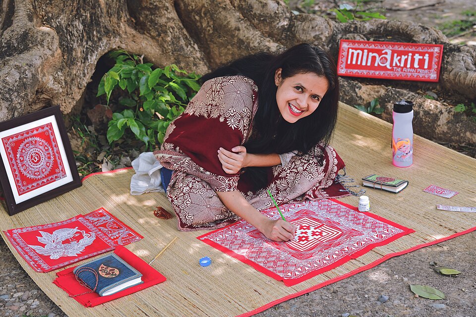 Aipan artist Minakshi Khati painting a white-on-red aipan design